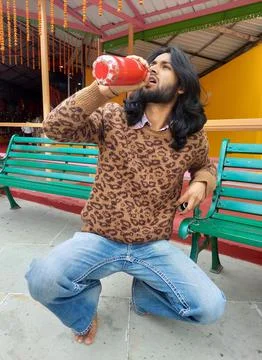 A good looking long haired and bearded Indian young man drinking water Stock Photos