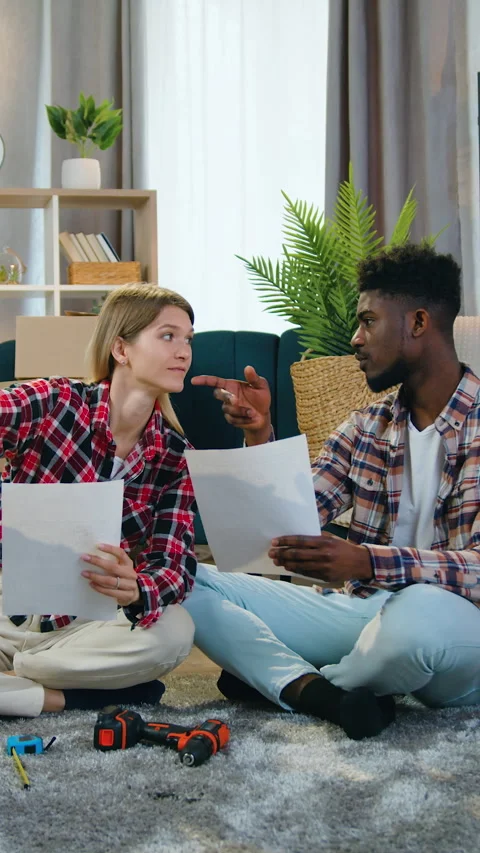 Good-looking man and girlfriend relaxing on fluffy carpet with plans of Stock Footage 332368068