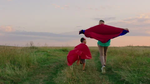 Good looking man and his charismatic son running in superheroes suits through Stock Footage 166843295