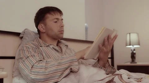 Good-looking man at home reading a book in his bed Stock-Footage 68420531