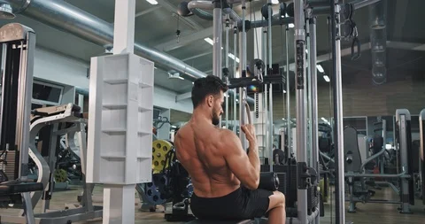 Good looking man lifting up the weights at gym for his biceps and triceps in a Video stock 116036218