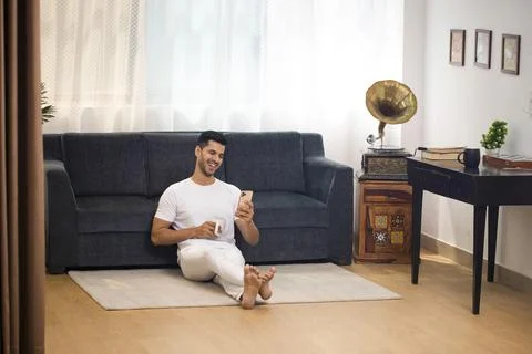 Good Looking Man Smiling While Looking At His Mobile Stock Photos