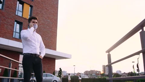 Good-looking man strolling outdoor and speaking on cellphone. Coronavirus Stock Footage 140288172