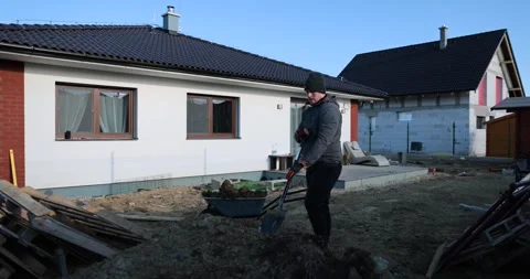 Good looking man worker throwing earth and mold in to garden wheelbarrow and rid Stock Footage 242036307