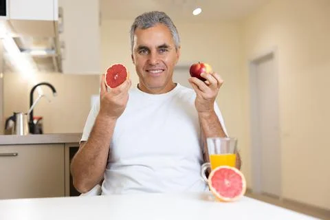 Good looking mature man eats fruits. Organic healthy food concept. Cheerful man Stock Photos