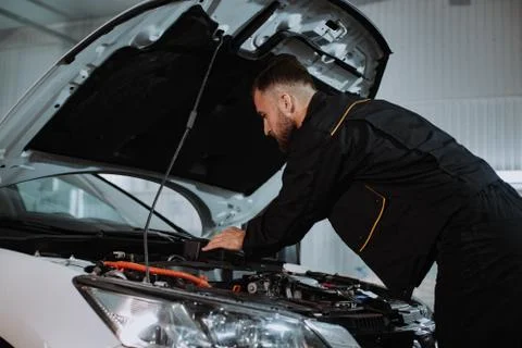 Good looking mechanic guy working on the engine of the car he solve the problem Stock Photos