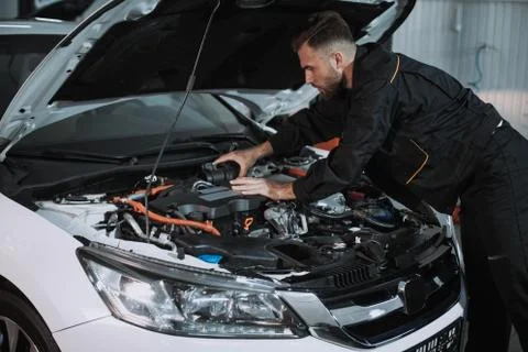Good looking mechanic guy working on the engine of the car he solve the problem Foto stock