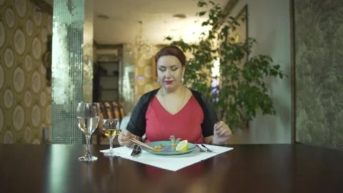 Good looking middle aged brunet female in red dress eating food with chopsticks  Stock Footage 137537338