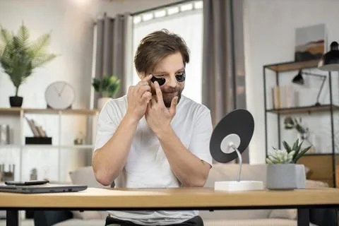 Good-looking modern caring young bearded man applying anti-aging collagen Stock Photos