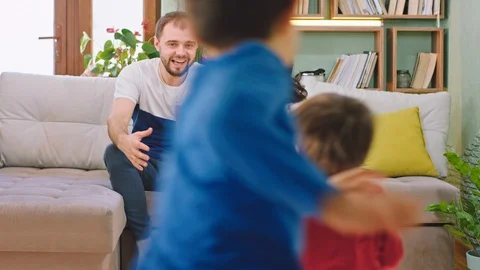 Good looking parents sitting on the sofa and happy hugging their two kids they Stock Footage 127915594