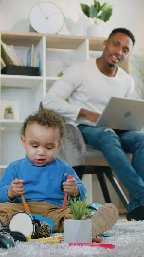 Good-looking positive caring 30-aged african american father uses computer and w Stock Footage 329437202