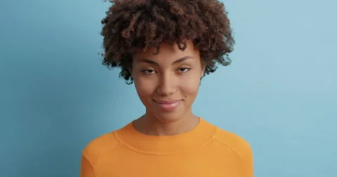 Good looking serious young Afro American woman with curly bushy hair looks Stock Footage 143625792