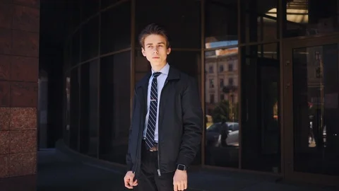 Good-looking serious young guy in classic clothes looking at screen of smart Stock Footage 92060763