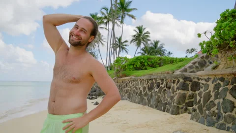 Good-looking smiling bearded young man with bare torso standing by the ocean Stock Footage 263528002