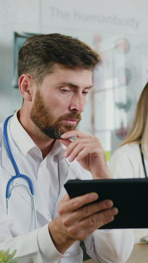 Good-looking successful skilled multiethnic men-medics browsing results on table Stock Footage 332997499