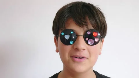A good looking teenage boy in sunglasses with sequins on the glasses makes faces Stock Footage 237167341
