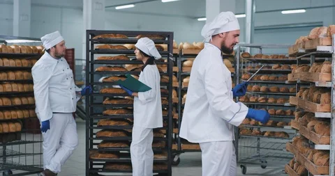 Good looking three bakers in a bakery after they load the bread on the shelves Stock Footage 122934446