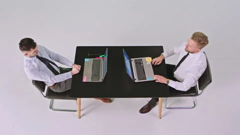 Good looking two office workers sitting on the same table in a white large Video stock 132435073