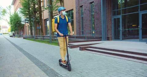 Good-looking young delivery guy riding electric kick scooter in business Stock Footage 140116185