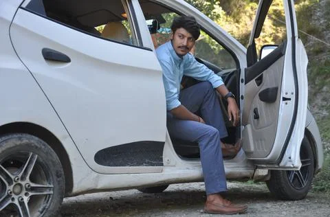 A good looking young guy looking away while sitting in car with open door  Stock-Fotos