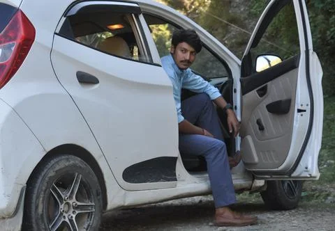 A good looking young guy looking away while sitting in car with open door  Foto stock