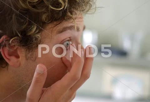 Good looking young man applying contact lens Stock Photos
