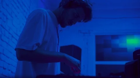 Good-looking young man with beard mixing music, looking at DJ booth. Portrait of Video stock 95929240