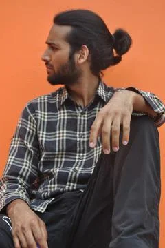 A good looking young man with beard and hair bun looking sideways  Stock Photos