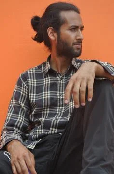 A good looking young man with beard and hair bun looking sideways  Stock Photos