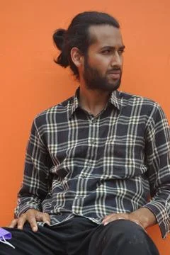 A good looking young man with beard and hair bun looking sideways  Foto stock