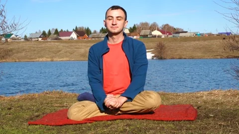A good-looking young man doing yoga on a jetty with tropical island backdrop Stock Footage 108062774