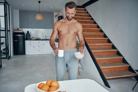 Good looking young man having breakfast while spending time at kitchen Photos