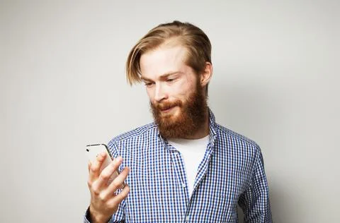 Good looking young man in smart casual wear using his smart phone and smiling Stock-Fotos