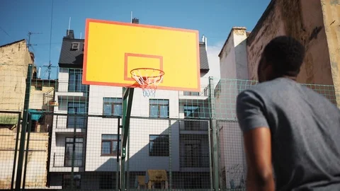 Good-looking young man throwing a ball to basketball hoop. Nice African student Stock Footage 92055122