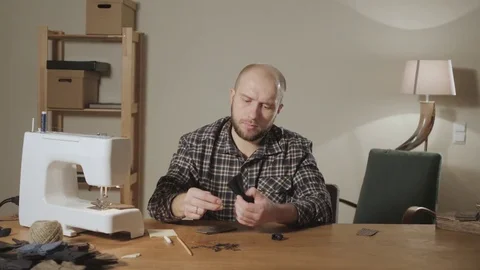 Good looking young man working as a tailor and using a sewing machine in a Stock Footage 82844934