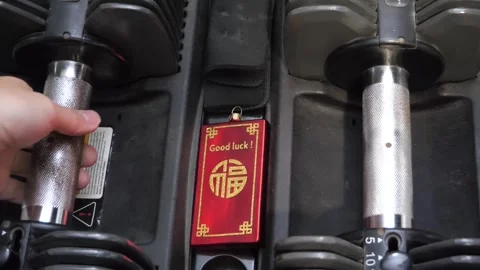 Good luck charm on a set of gym weights with a hand picking and putting it back Stock Footage 256866840