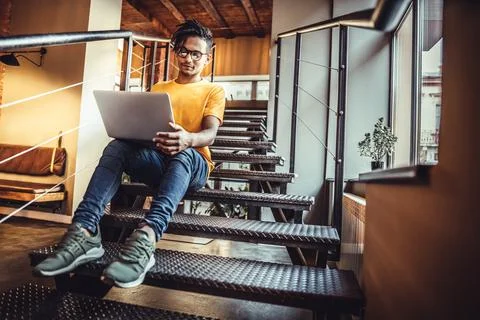 This is a good place to work and study. A young guy works for a laptop in a c Stock Photos