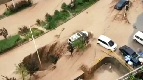 Good Samaritans team up to pull a car away from a huge sinkhole Stock Footage 106297989