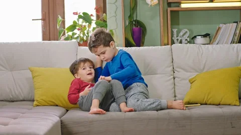 Good small friends on the sofa two kids spending funny time together playing the Stock Footage 127706114