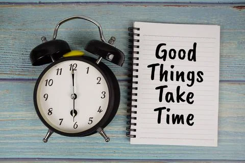 Good Things Take Time text written on notepad with alarm clock on wooden ba.. Stock Photos