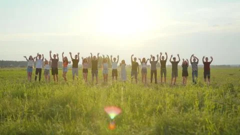Goodbye concept. A large group of students wave their hands at sunset. Stock Photos