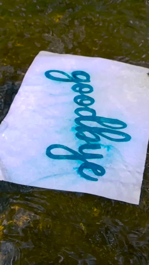 Goodbye Letter Floating Away in a Shallow River Symbolizing Farewell Stock Footage 335634711
