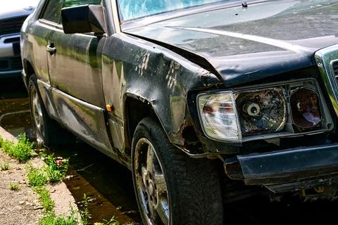 Goodbye.Old car with rusty wing,broken headlight and flat tire 库存照片