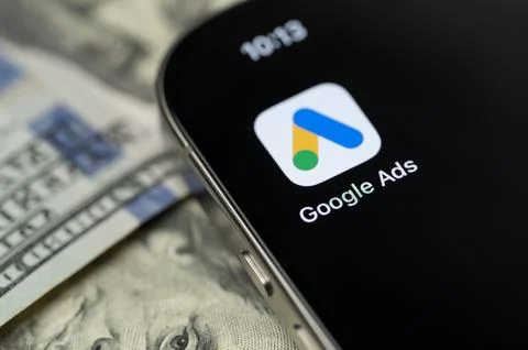 Google ads app on smartphone screen with dollar background Stock Photos