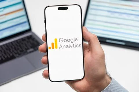Google Analytics logo on the screen of mobile phone in mans hand Stock Photos