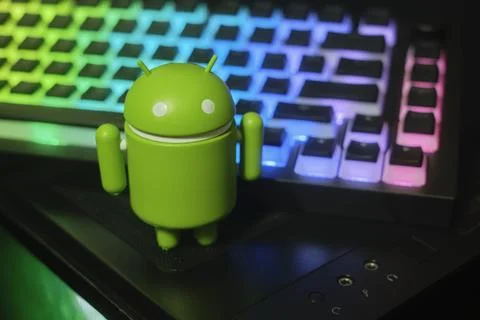 Google Android figure standing on computer with keyboard in the background Stock-Fotos