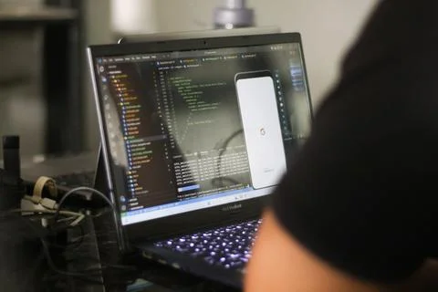 Google Android figure standing on desk with code in the background 스톡 사진