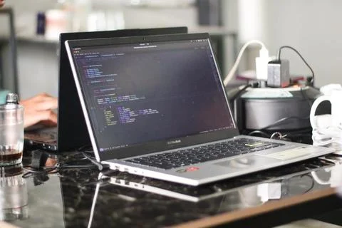 Google Android figure standing on desk with code in the background Stock Photos
