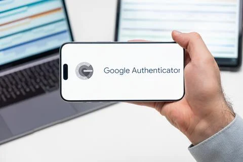 Google Authenticator logo of app on the screen of mobile phone held by man Stock Photos