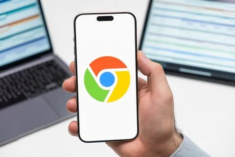 Google Chrome logo on the screen of mobile phone in mans hand Stock Photos